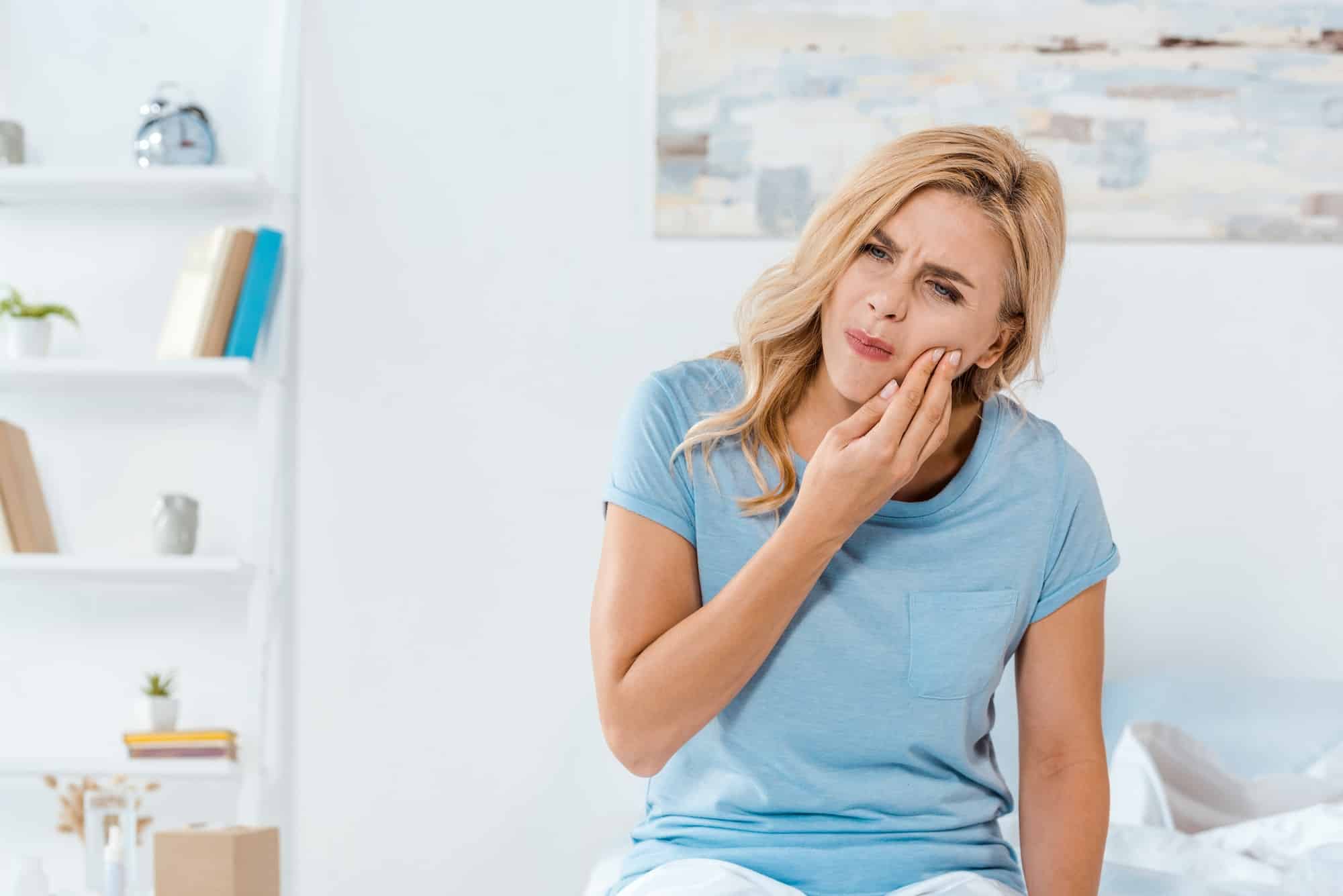 upset woman touching cheek while having tooth ache